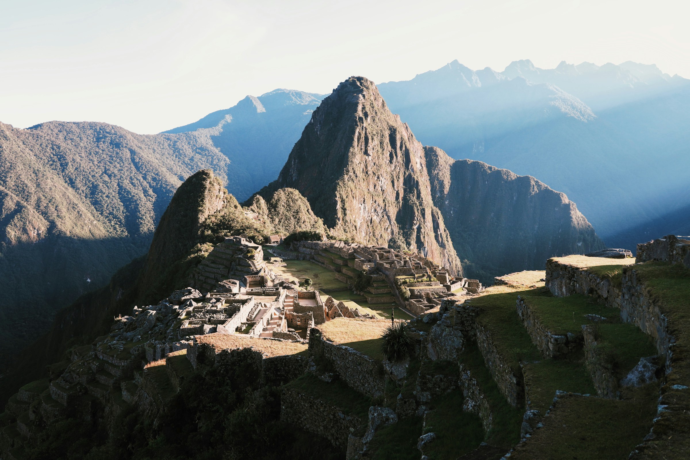Machu Picchu's quiet stone terraces beneath a mountain peak in soft morning light