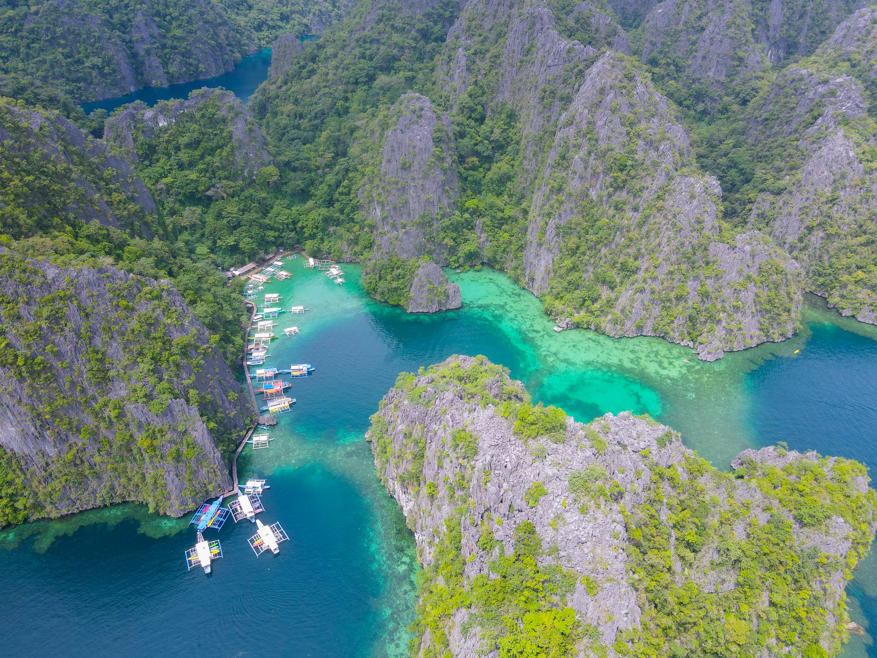 Outrigger boats in a turquoise lagoon surrounded by limestone islands in Coron, Philippines