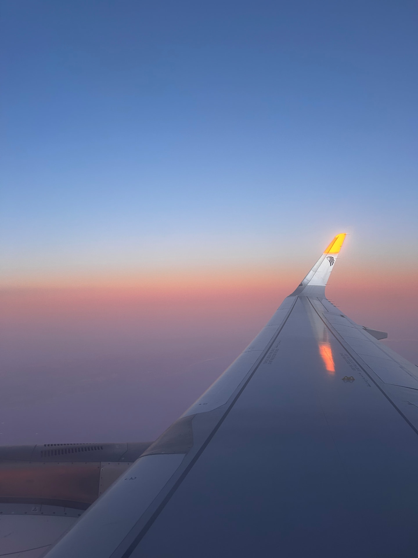 An airplane wing at sunset above the clouds